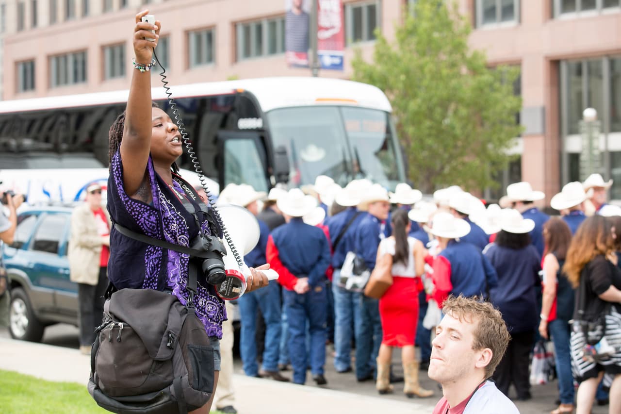 LUNES 18 DE JULIO. 11:16 AM. Una manifestante contra Donald Trump grita consignas a la delegación de Texas que espera el autobús que los llevará a la convención.