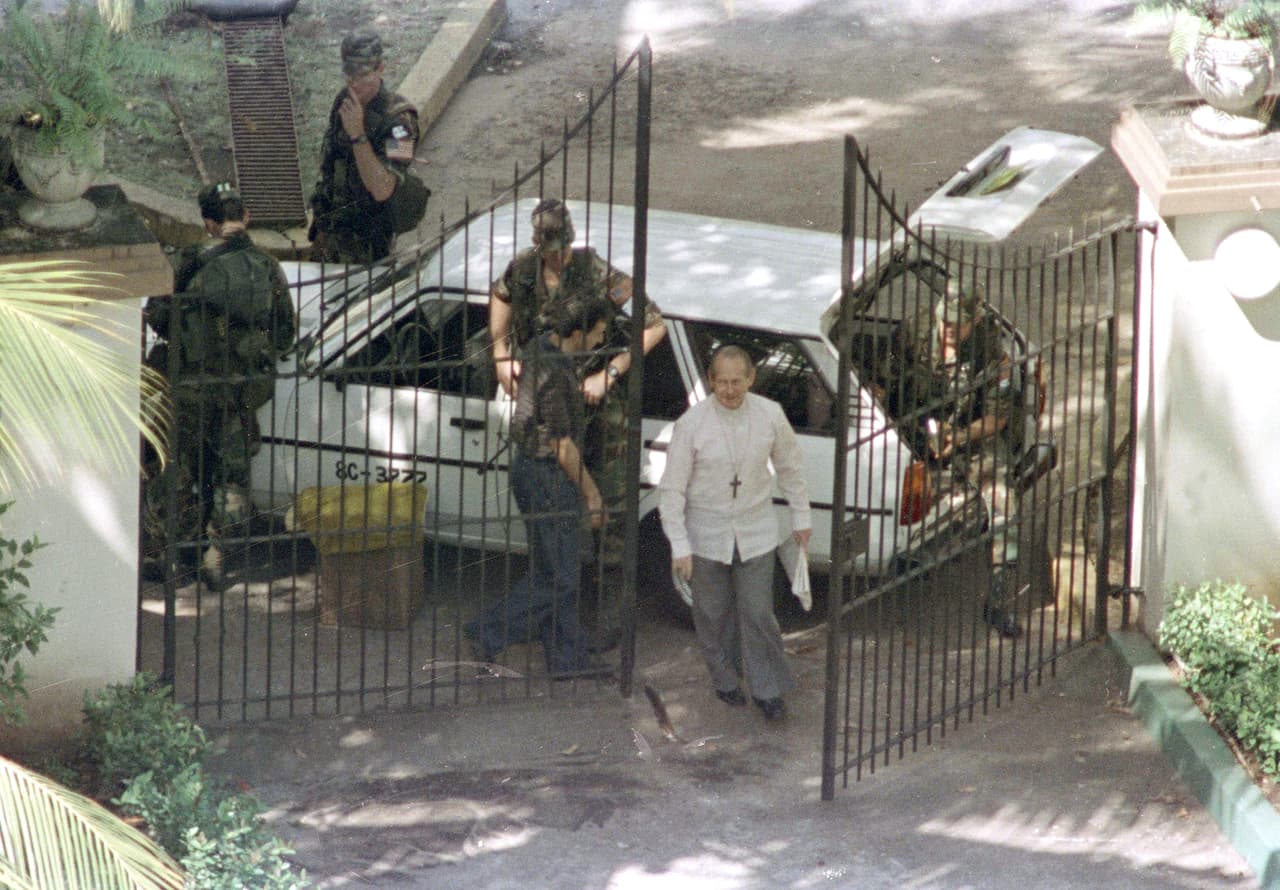 Vatican ambassador Jose Sebastian Laboa walks through the gate past American soldiers into the embassy compound in Panama City where Gen Manuel Noriega sought refuge during the invasion, Jan. 1, 1990. Noriega surrendered two days later.