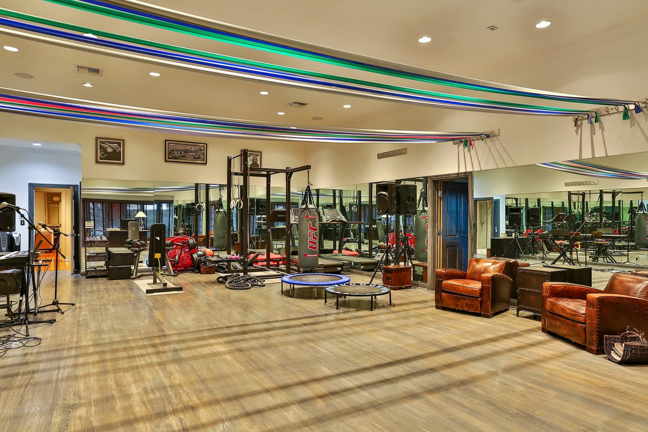 ¡Así se mantiene en forma! Un vistazo a su gimnasio, con aparatos, pesas, un costal de box y, a un costado, un pequeño estudio para cuando llegue la inspiración a media sesión de gym.