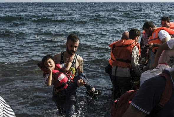 Un refugiado sirio lleva a un niño en la isla de Lesbos.