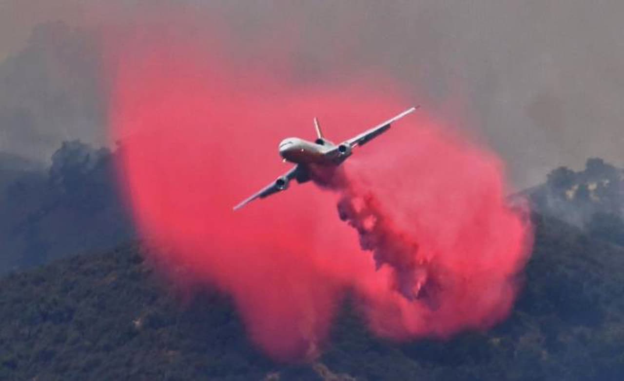 Avión DC-10 suelta químico retardante sobre las llamas del incendio Álamo.