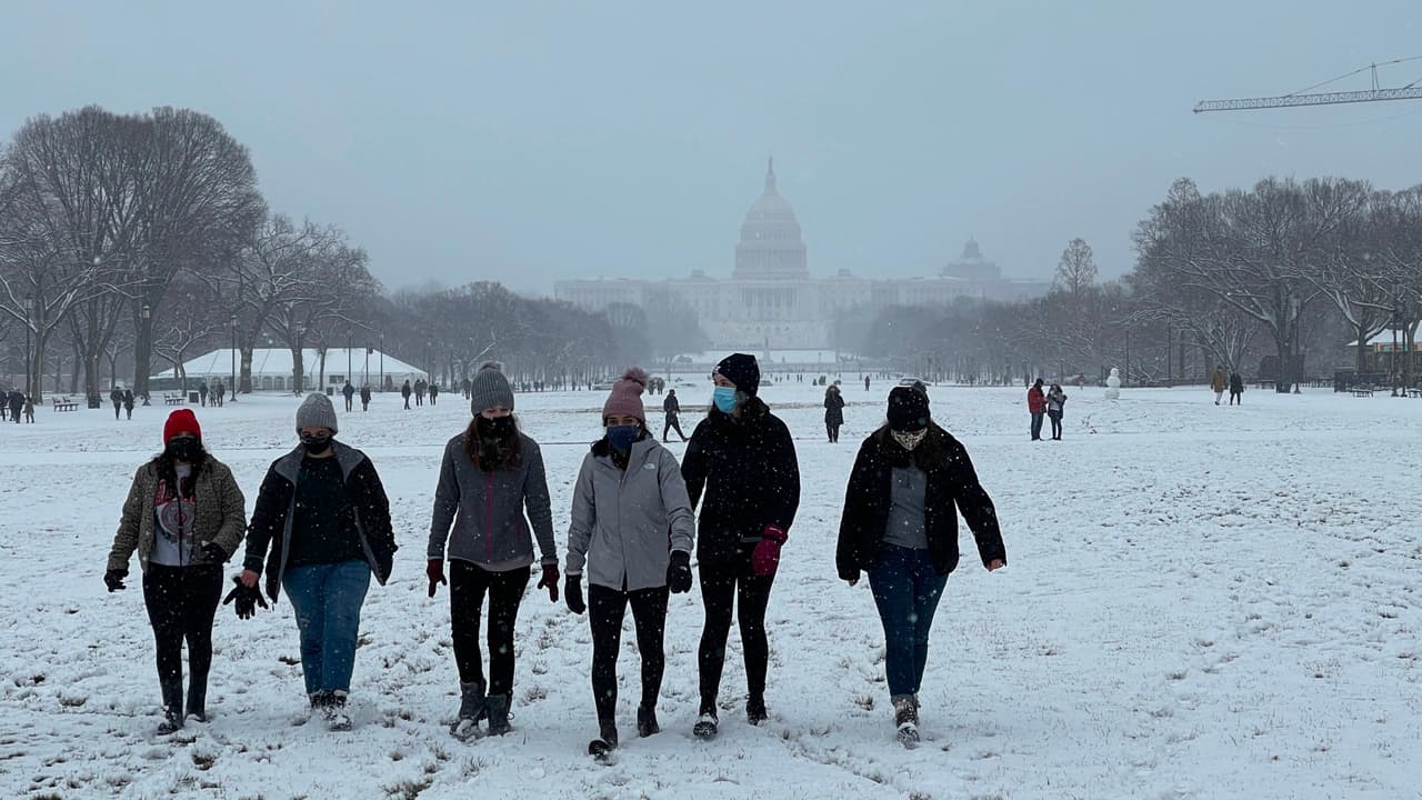 Un grupo de mujeres camina alrededor del National Mall en Washington DC, mientras a la distancia se visualiza el Capitolio. Es la nevada más fuerte en esta área del país en los últimos dos años.
