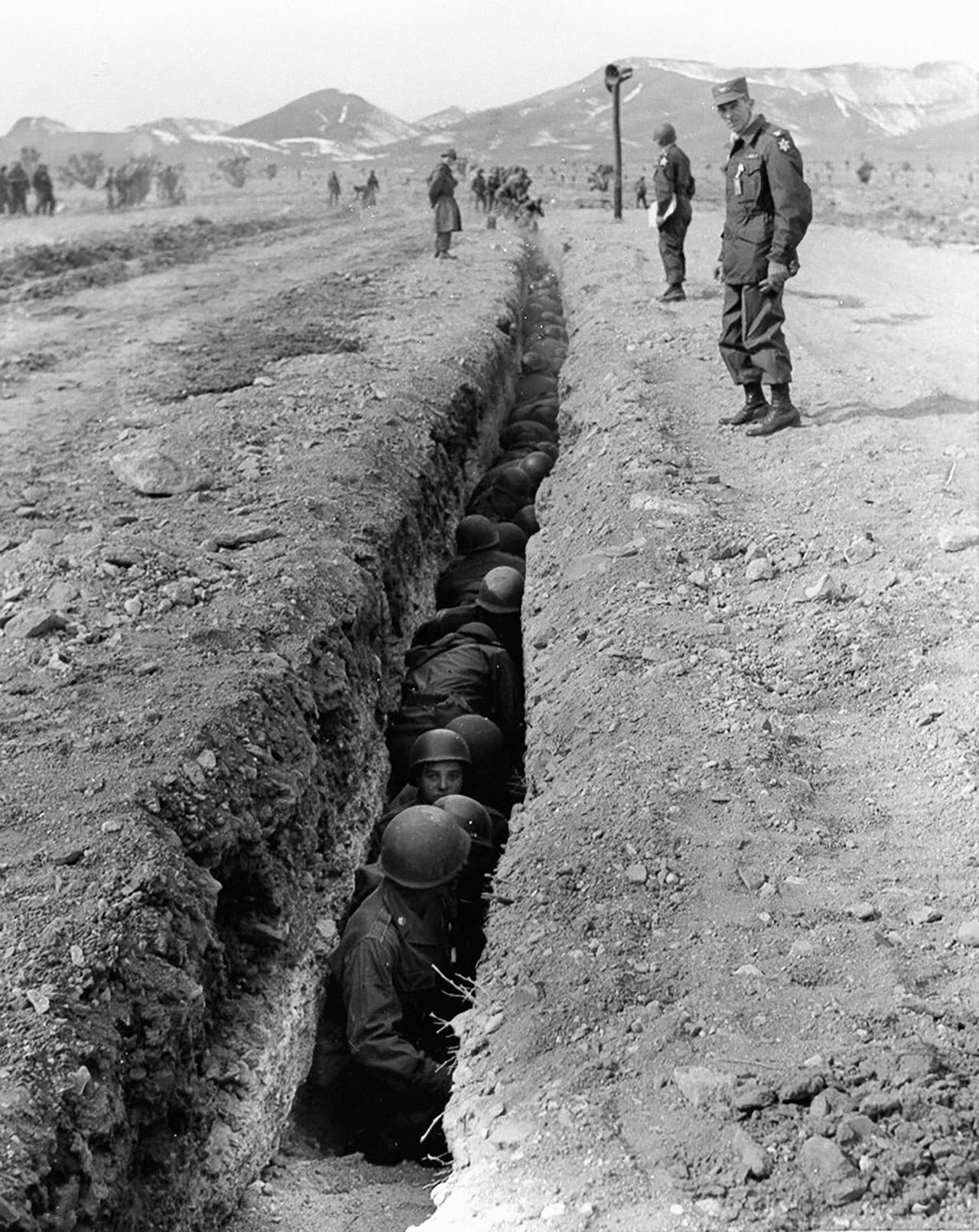 Soldados del ejercito de los EEUU protegidos en trincheras de seis pies de profundidad construidas a dos millas de las explosiones atómicas. Se investigaba el daño infringido a los equipos expuestos directamente a la onda expansiva.
<br>