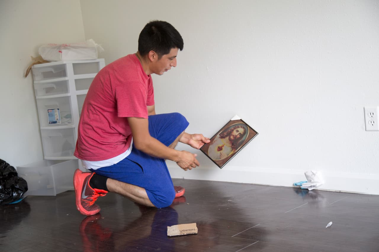 Abraham Fuentes, de 27 años, recoge un cuadro con la imagen del sagrado corazón que antes colgaba en una de sus paredes.