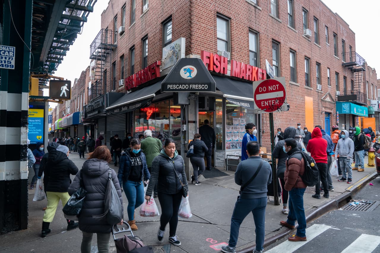 Docenas de personas hacen cola en las afueras del mercado Seatide Fish & Lobster para comprar pescado en el barrio de Jackson Heights, de Queens.