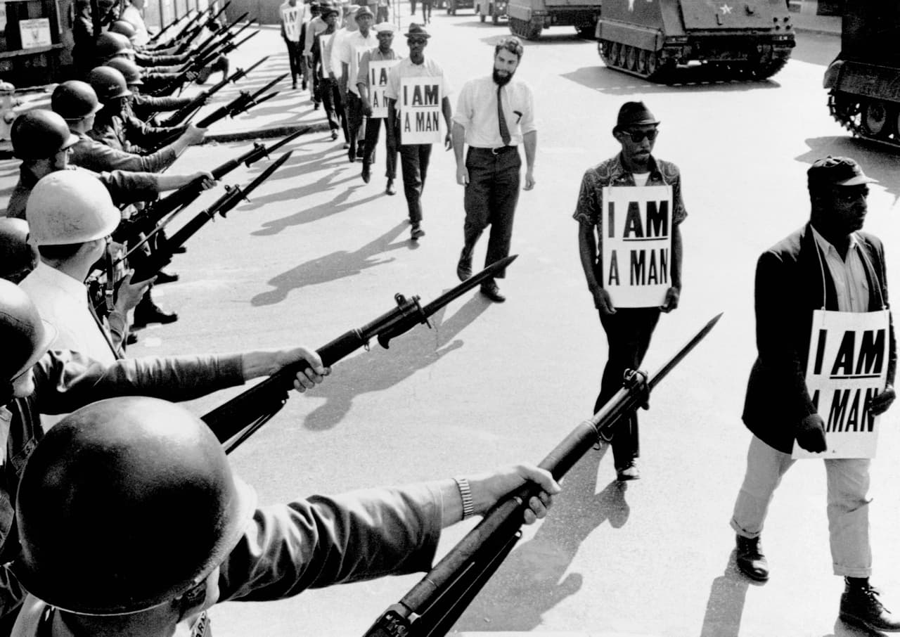 Civil Rights activists are blocked by National Guardsmen brandishing bayonets while trying to stage a protest on Beale Street in Memphis, Tennessee. The marching demonstrators, who are wearing signs which say "I Am A Man," are also flanked by tanks.