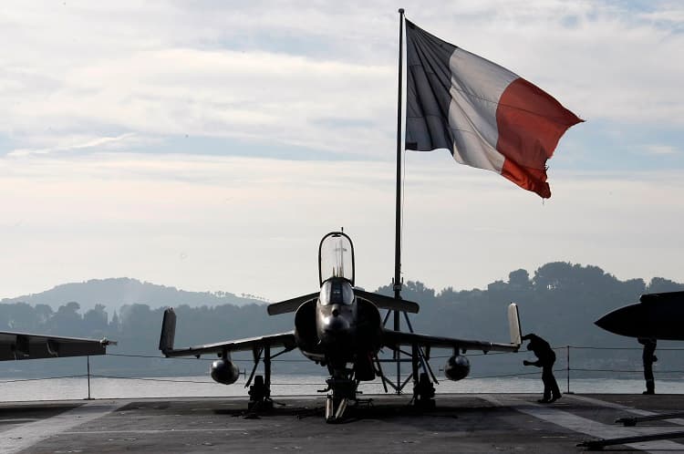 Una bandera francesa junto a un avión en el buque Charles de Gaulle.