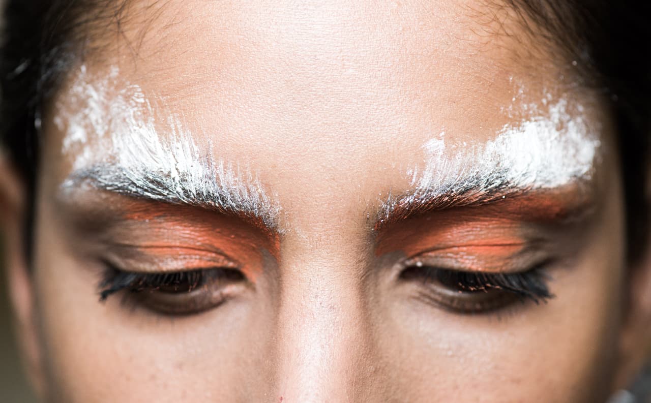 Las cejas con efecto de brochazo blanco formaron parte de la propuesta de maquillaje del desfile de 
<a href="https://www.instagram.com/cimoneuk/">Cimone</a>. Los párpados con efecto deslavado en tono naranja complementaron el beauty look.
<br>