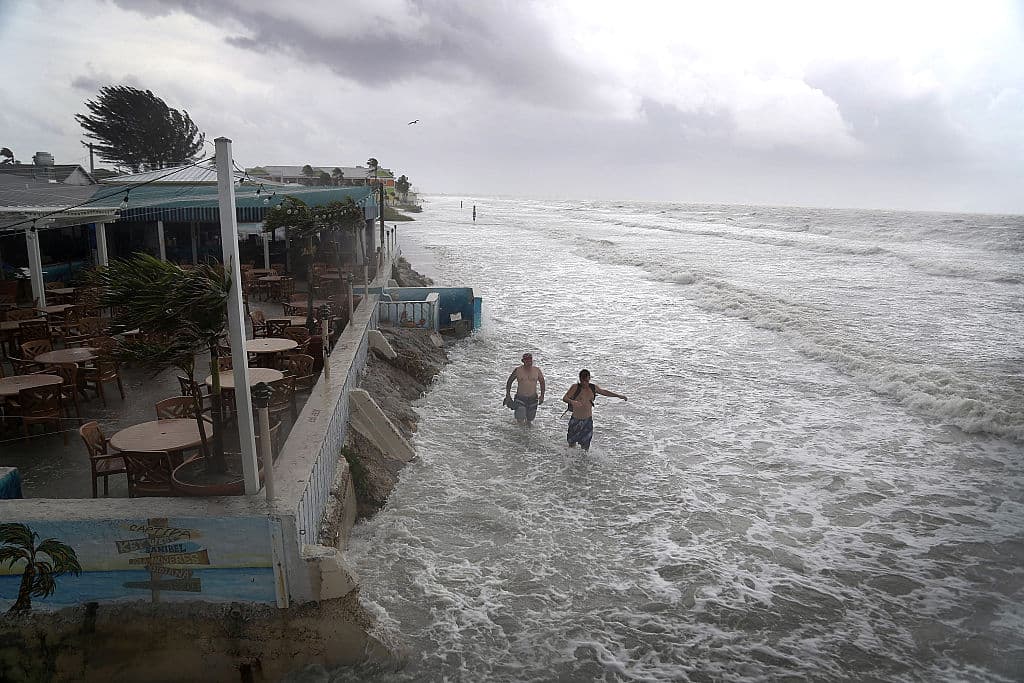 Gente caminando a lo largo de la playa de Fort Myers, donde la alta marea provocada por la tormenta borró la línea de arena