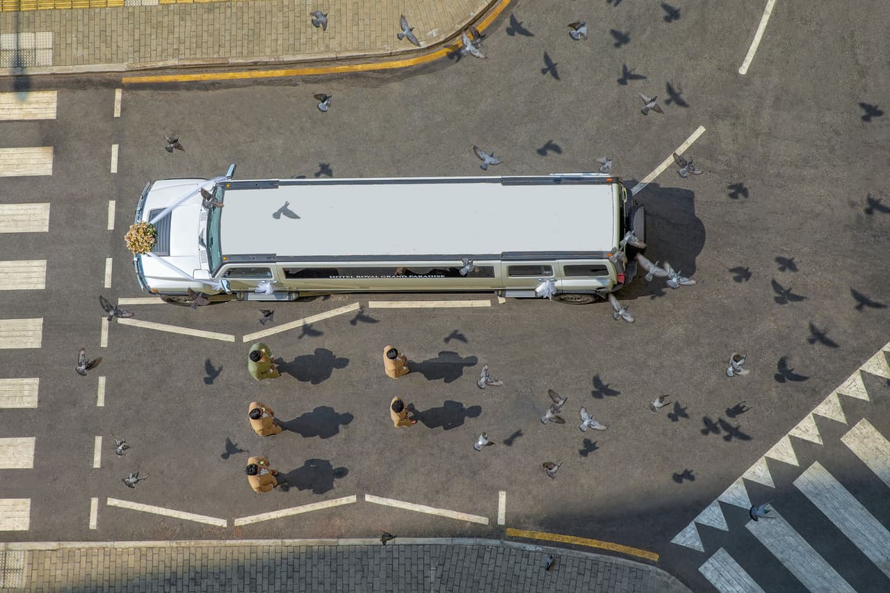 Esta imagen ganó en la categoría ‘desde arriba del concurso Fotógrafo Internacional de Bodas 2021.
<br>
<br>“Tan pronto como vi el auto del novio estacionado en la carretera en ese punto, decidí que era un gran momento para una foto. Creo que la bandada de palomas que volaron cuando nadie esperaba la hizo más atractiva”, 
<a href="https://www.instagram.com/foto_stationlk"><u>explicó el autor</u></a>.