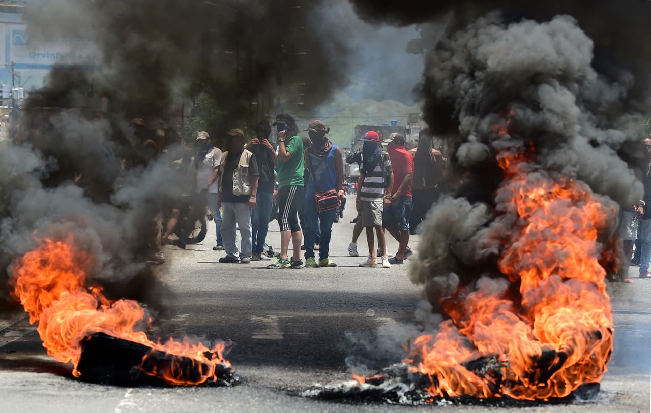 Manifestantes anti-gobierno tras una barricada en Valencia. Después de conocerse el ataque al fuerte militar, vecinos salieron a las calles y se enfrentaron con la Guardia Nacional Bolivariana.