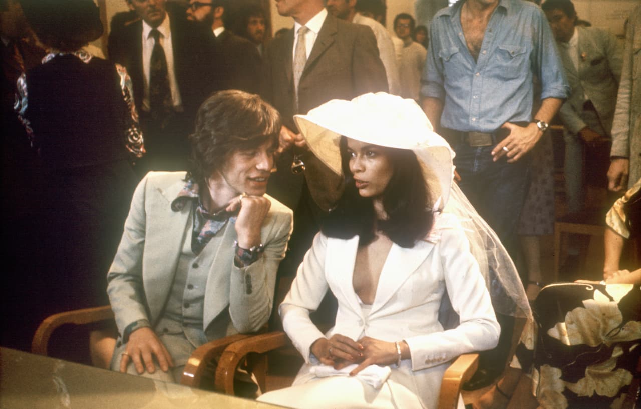 Si esta fuera una lista de los vestidos más atípicos de la historia, quizás el esmoquing de falda y sombrero de Bianca Jagger, creado por Yves Saint Laurent, sería el que debería encabezar la lista. Para su matrimonio, en 1971 con Mick Jagger, el cantante de los Rolling Stone innovó en la moda para las novias.
