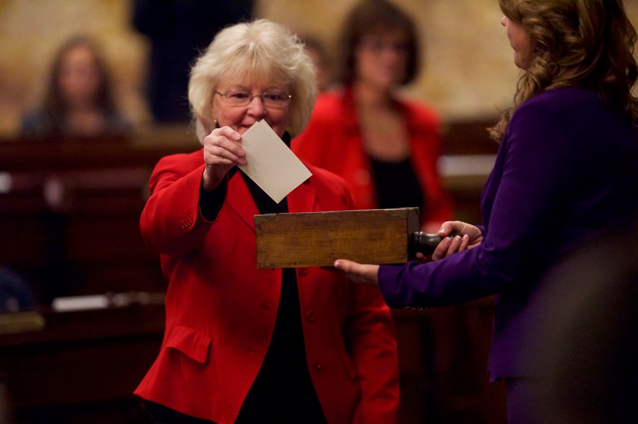 Una electora coloca su voto en la urna, durante la jornada de votación del Colegio Electoral en Harrisburg, Pensilvania.