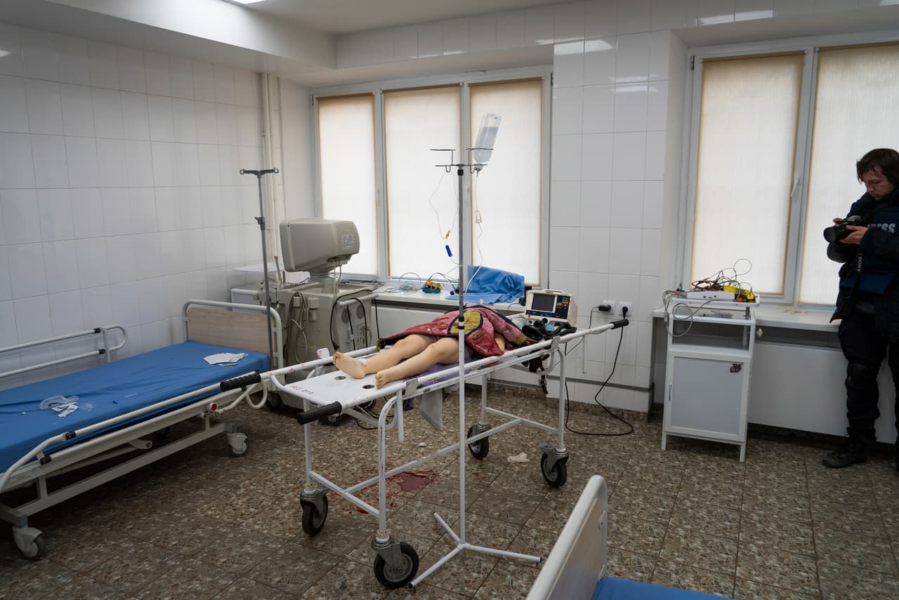 Associated Press photographer Evgeniy Maloletka takes a photo of the lifeless body of a girl, killed from shelling of a residential area, at the city hospital of Mariupol, eastern Ukraine, Sunday, Feb. 27, 2022. (AP Photo/Mstyslav Chernov)
