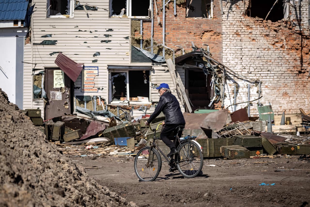 Un hombre monta en bicicleta frente a un edificio destruido. Los residentes transitan caminando o en bicicleta por un escenario de catásatrofe: donde antes había casas o edificaciones ahora hay cráteres y ruinas. 
<b>Todavía no está claro cuántos civiles han muerto en Trostianets. </b>