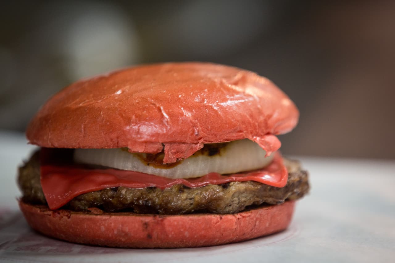 Esta fenomenal hamburguesa incluye pan rojizo y también queso del mismo tono.