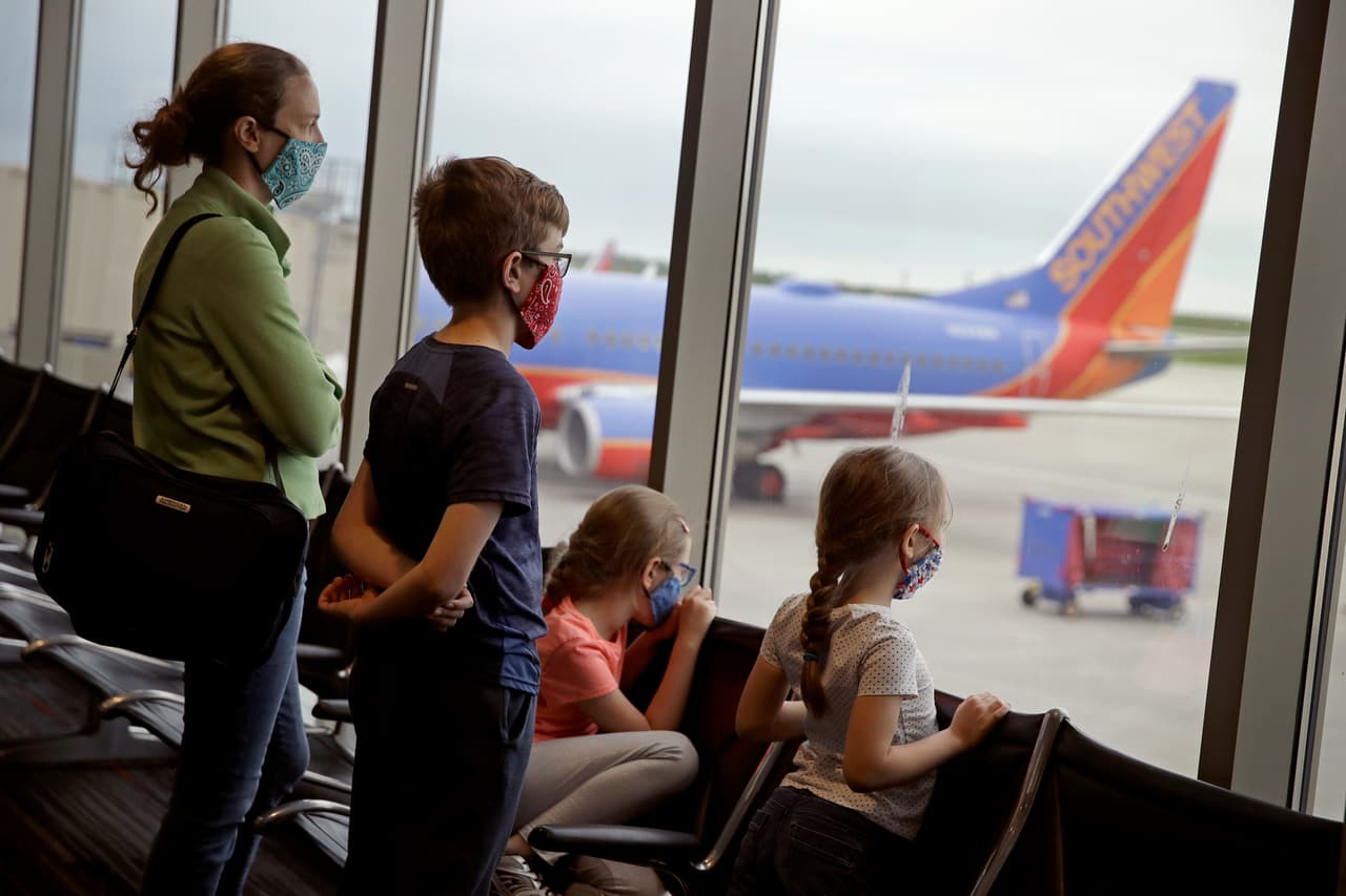 Una familia llevando mascarillas espera para abordar un vuelo de Southwest Airlines en el aeropuerto internacional de Kansas City, en Missouri.