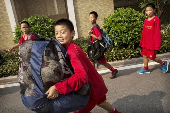 Este niño carga con una bolsa de balones de fútbol listo para entrenar.