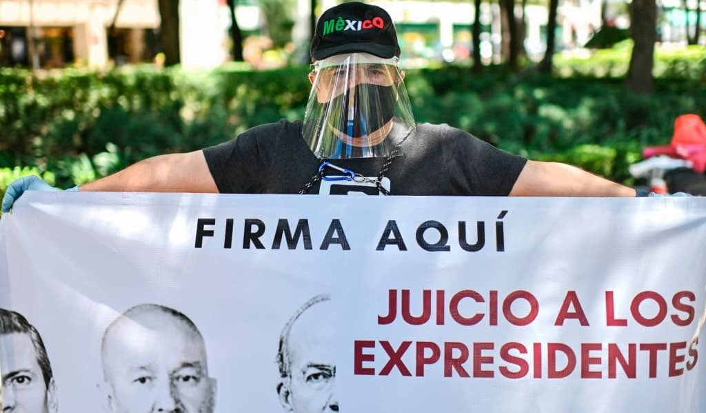 An activist displays a banner during the collection of signatures seeking the prosecution of former Mexican presidents for corruption, in Mexico City, on August 31, 2020.