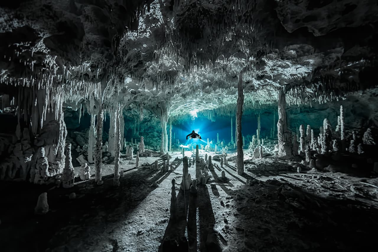 Los espeleotemas, formados por depósitos minerales en las cuevas, proyectan largas sombras en el cenote Dos Pisos, en Quintana Roo, México. Fue la imagen ganadora en la categoría ‘exploración’ del Premio de Fotografía Oceánica 2021.