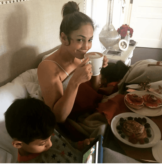 Recién levantada, en compañía de su pequeño, el carisma radiante de JLo se advierte mientras bebe un Capuccino en cama.