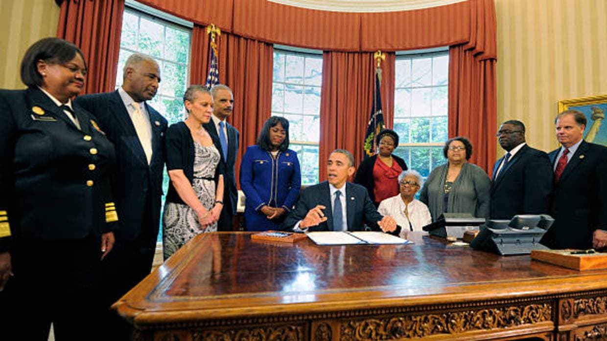 El expresidente Barack Obama (C) firma un proyecto de ley en la Oficina Oval designando la Medalla de Oro del Congreso para conmemorar a las jóvenes asesinadas en el atentado de 1963 contra la Iglesia Bautista de la calle 16 en Birmingham, Alabama, por supremacistas blancos. El ex fiscal federal Doug Jones está en el extremo derecho.