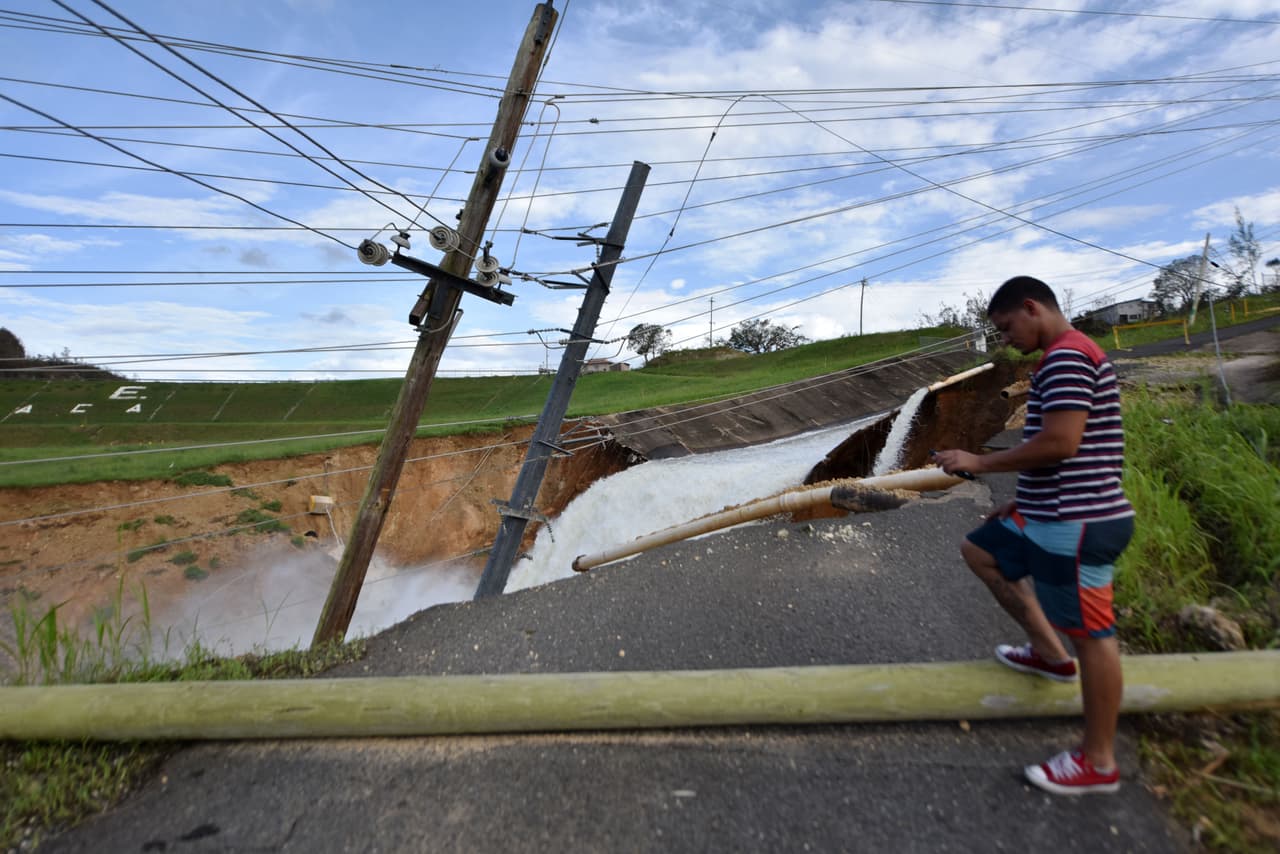 A young man surveys the overflow from Lake Guajataka in San Sebastian, western Puerto Rico, on September 23, 2017 following passage of Hurricane Maria. Puerto Rico Governor Ricardo Rossello called Maria the most devastating storm in a century after it destroyed the US territory's electricity and telecommunications infrastructure. / AFP PHOTO / HECTOR RETAMAL (Photo credit should read HECTOR RETAMAL/AFP/Getty Images)