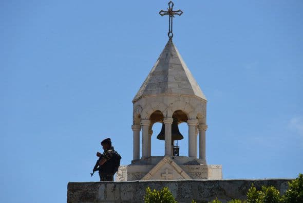 Un miembro de las fuerzas de seguridad palestinas vigila desde el techo de la Iglesia de la Natividad.