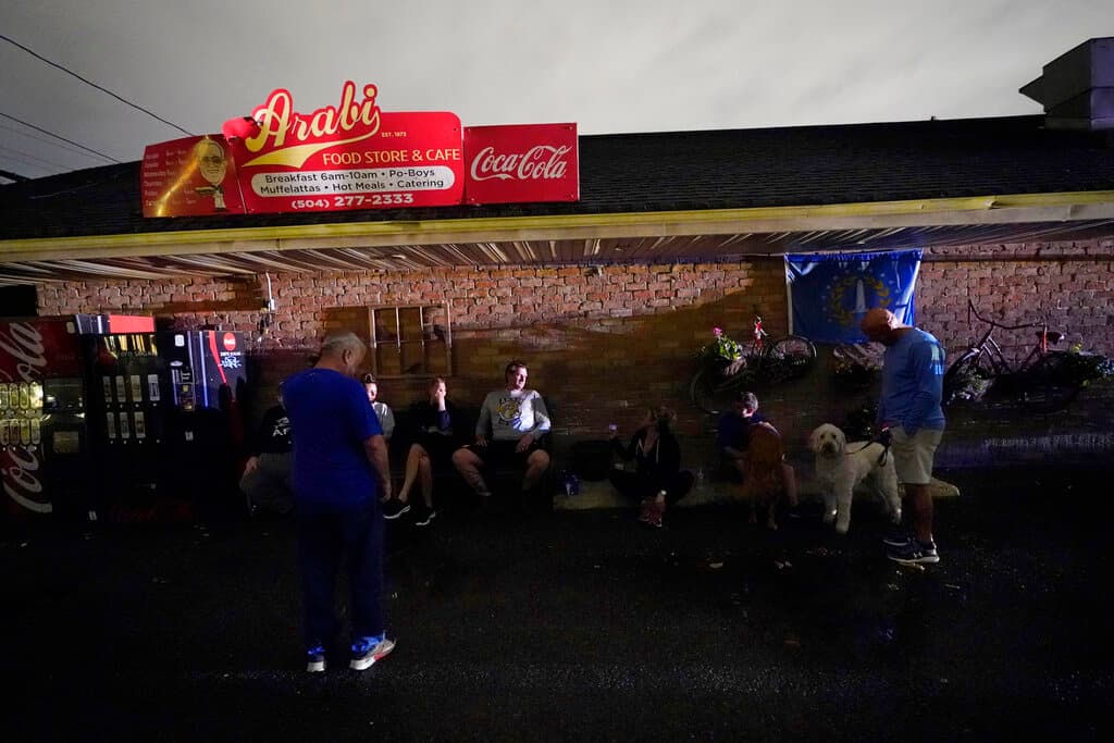 Max Landry, en el centro, propietario de la tienda Arabi Food, se sienta con los residentes, algunos de los cuales están desplazados de sus casas dañadas, después del paso del tornado.