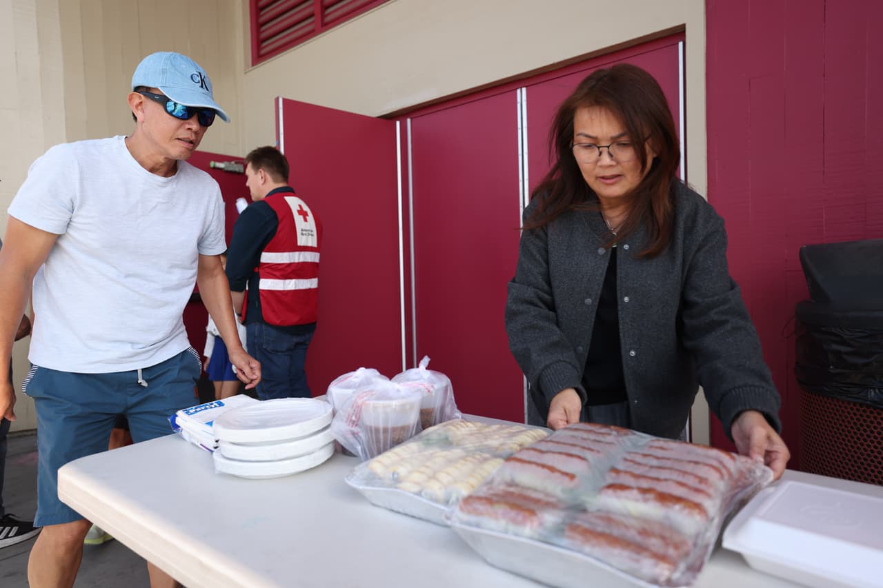 La ex concejala de Garden Grove, Thu-Ha-Nguyen, reparte comida donada por un restaurante local a las afueras de la escuela secundaria Ocean View para los evacuados el sábado 23 de mayo de 2026 en Huntington Beach, California. (Foto AP/Jill Connelly)