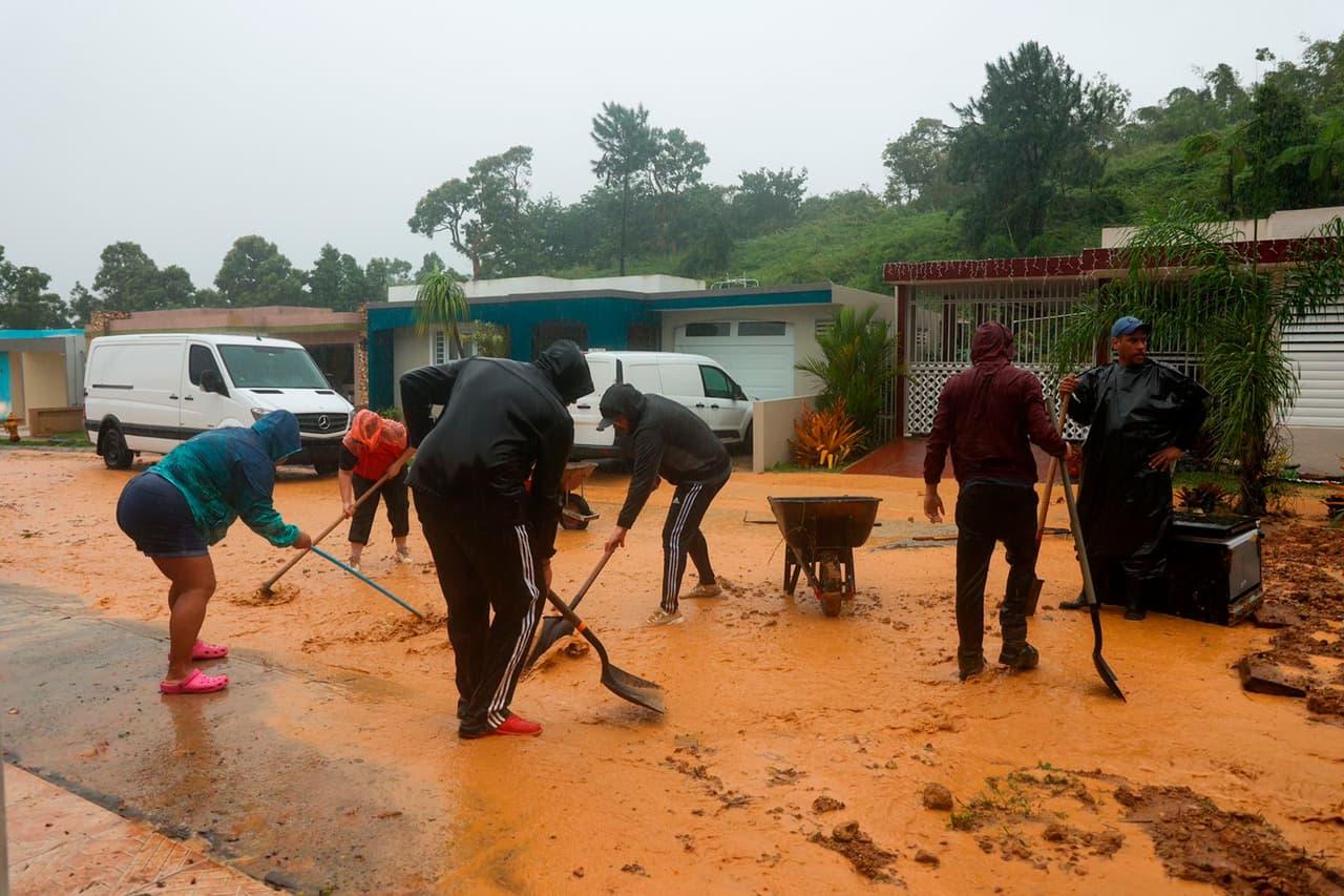 Luma, la compañía que opera la transmisión y distribución de energía, dijo que el mal tiempo, incluidos vientos de 80 mph, había interrumpido las líneas de transmisión, lo que llevó a "un apagón en toda la isla". En la foto, la gente limpia una carretera tras un deslave en Cayey.