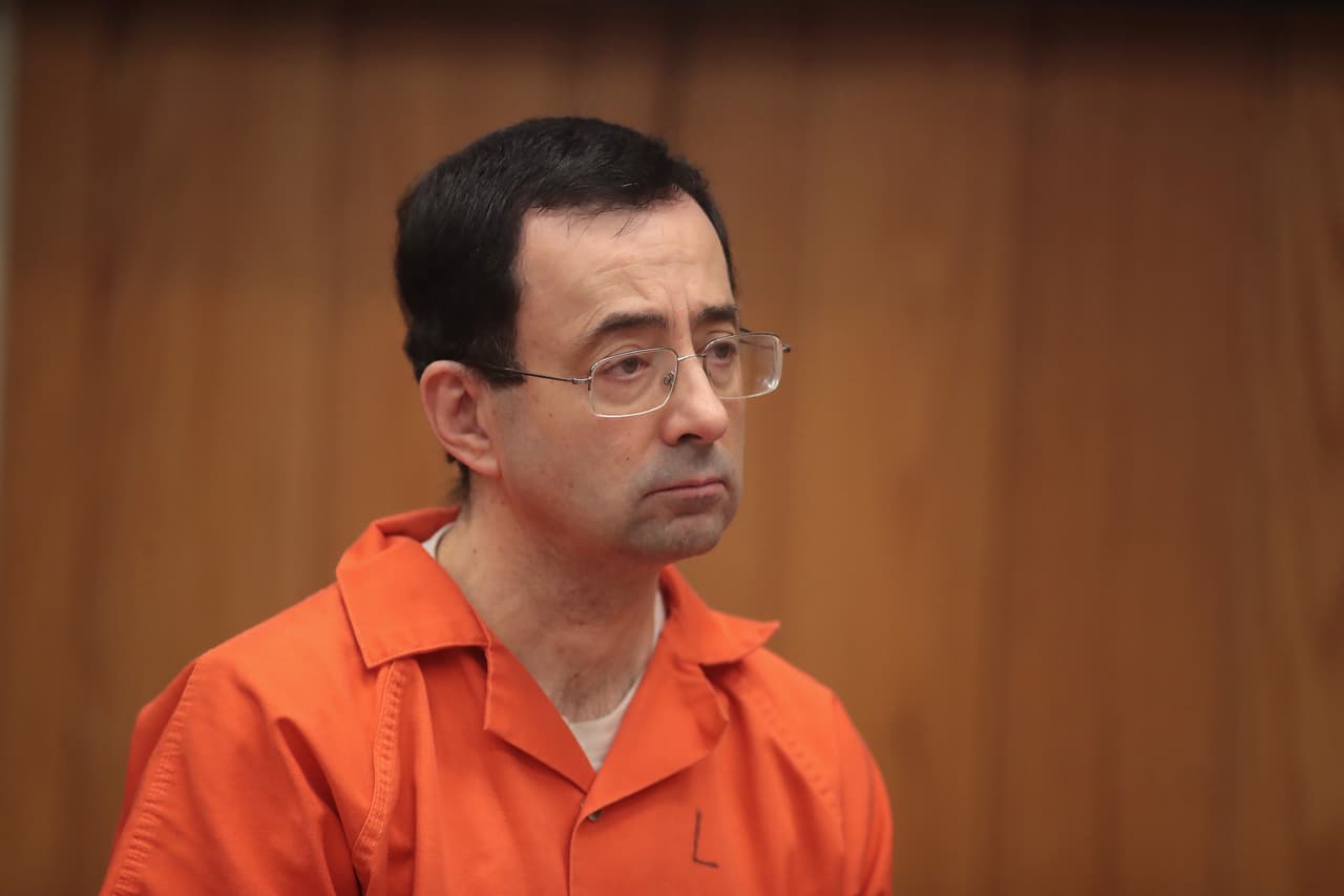CHARLOTTE, MI - FEBRUARY 05: Larry Nassar stands as he is sentenced by Judge Janice Cunningham for three counts of criminal sexual assault in Eaton County Circuit Court on February 5, 2018 in Charlotte, Michigan. Nassar has been accused of sexually assaulting more than 150 girls and young women while he was a physician for USA Gymnastics and Michigan State University. Cunningham sentenced Nassar to 40 to 125 years in prison. He is currently serving a 60-year sentence in federal prison for possession of child pornography. Last month a judge in Ingham County, Michigan sentenced Nassar to an 40 to 175 years in prison after he plead guilty to sexually assaulting seven girls. (Photo by Scott Olson/Getty Images)