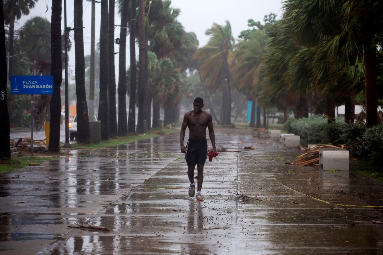 Un hombre camina bajo una intensa lluvia en Santo Domingo, República Dominicana, el 30 de julio. La tormenta tropical Isaías provocó apagones, inundaciones y pequeños deslaves en este país y en Puerto Rico el jueves, antes de ganar fuerza y convertirse en huracán en su avance hacia Bahamas y la costa este de Estados Unidos.