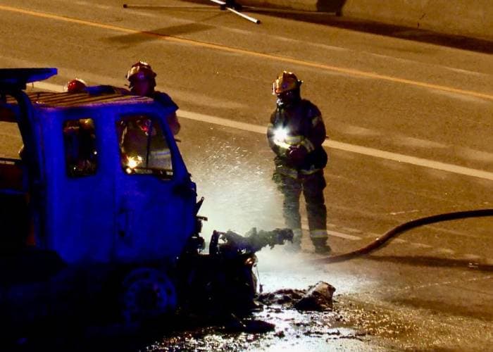 Bomberos trabajando en la grúa que se incendió tras el accidente.