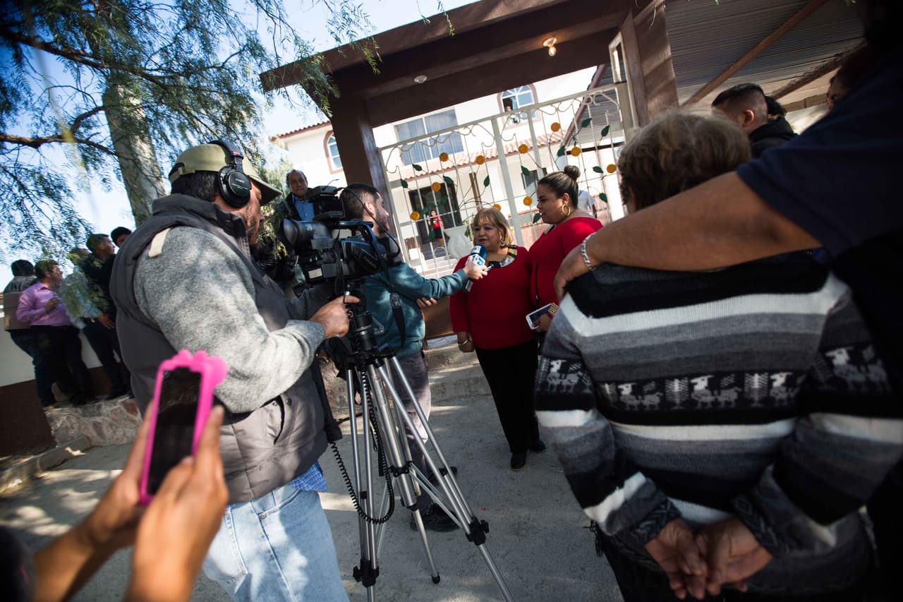 Dos periodistas de EFE entrevistan a dos señoras que viajaron desde otra ciudad para venir a los XV de Rubí, mientras otra señora graba la escena con su celular.
