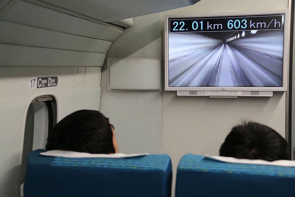 This Central Japan Railway hand out picture shows passengers watching a monitor in the company's seven-car maglev -- short for "magnetic levitation" -- train while setting a new world speed record in a test run near Mount Fuji, clocking more than 600 kilometres (373 miles) an hour on April 21, 2015. The new record came less than a week after the company clocked 590kph, by breaking its own 2003 record of 581 kph. AFP PHOTO / JIJI PRESS ==JAPAN OUT== (Photo credit should read JIJI PRESS/AFP/Getty Images)