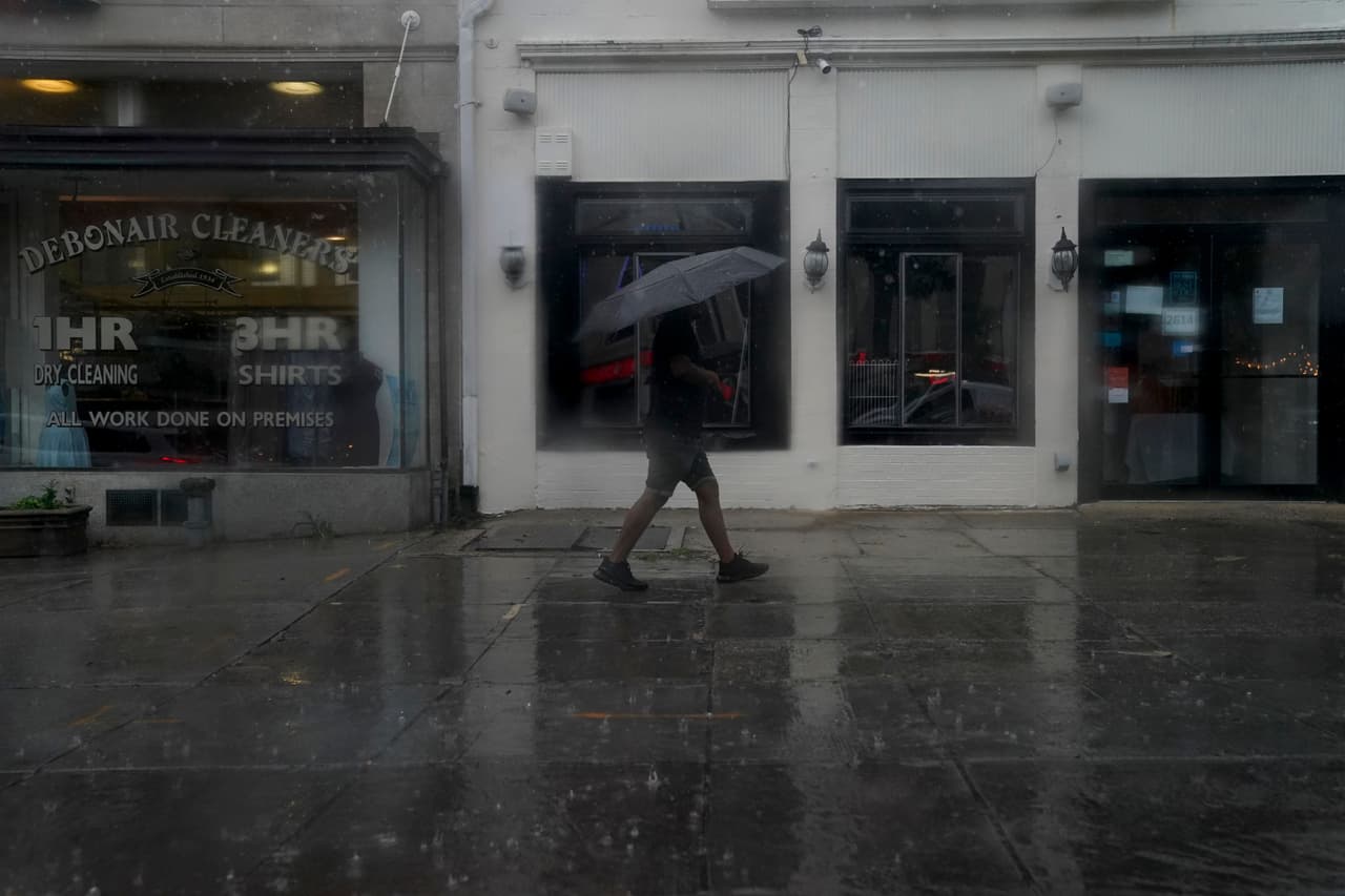 A pedestrian carries an umbrella while walking through rain in Washington, DC, on August 7, 2023. A tornado watch is in effect for the area, with heavy rain, strong winds, and hail expected. (Photo by Stefani Reynolds / AFP) (Photo by STEFANI REYNOLDS/AFP via Getty Images)