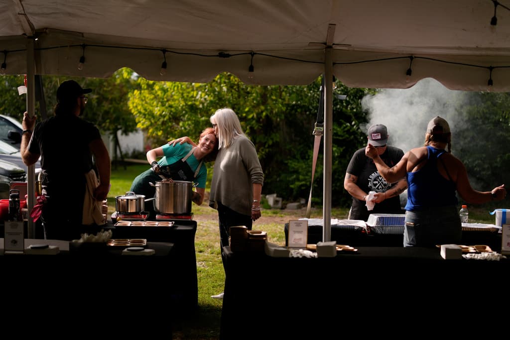 Mary Berry, directora ejecutiva del Berry Center, a la derecha, saluda a Randi Densford, a la izquierda, con un beso en la cabeza, mientras cocina durante el evento de degustación Beef Bash 2025 en el Berry Center, el sábado 11 de octubre de 2025, en New Castle, Kentucky.