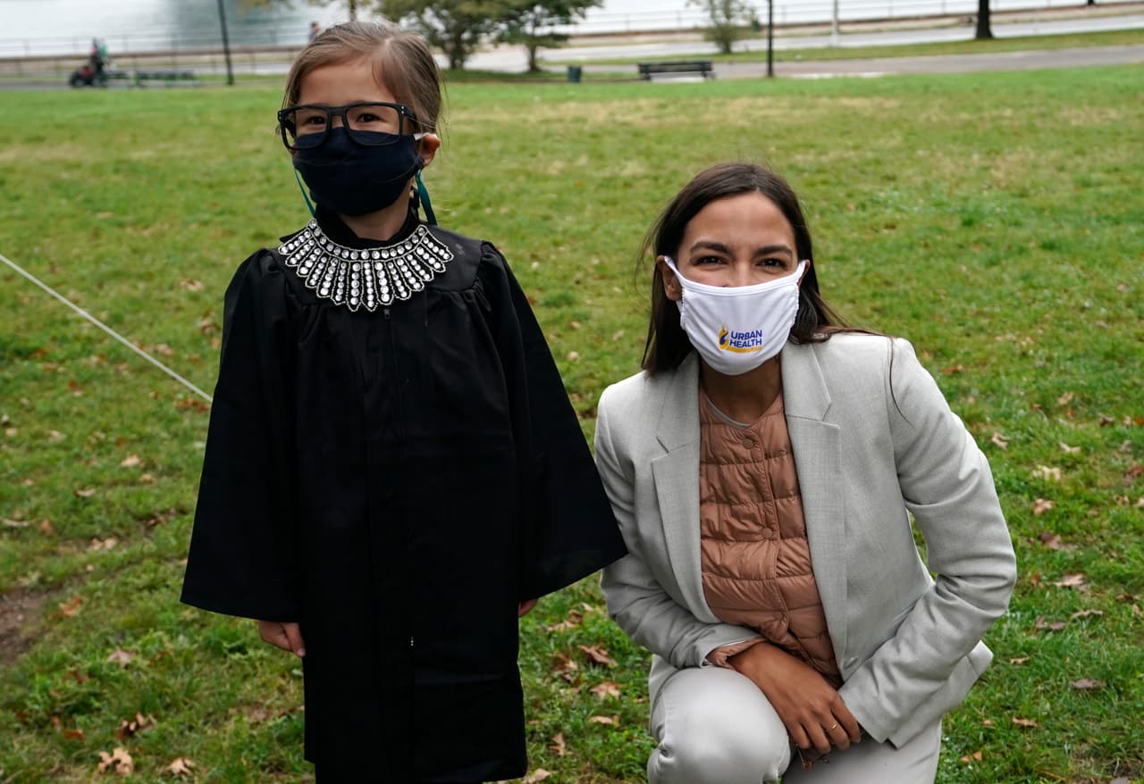 La representante estadounidense 
<b>Alexandria Ocasio-Cortez</b> posa con Halina Nix, quien está vestida como jueza de la Corte Suprema 
<b>Ruth Bader Ginsburg</b>, fallecida en septiembre, en un evento de campaña en el vecindario de Astoria de la ciudad de Nueva York el 28 de octubre de 2020. Ocasio-Cortez habló con los residentes de Astoria sobre la importancia de votar en las próximas elecciones, mientras distribuyó calabazas a los niños.