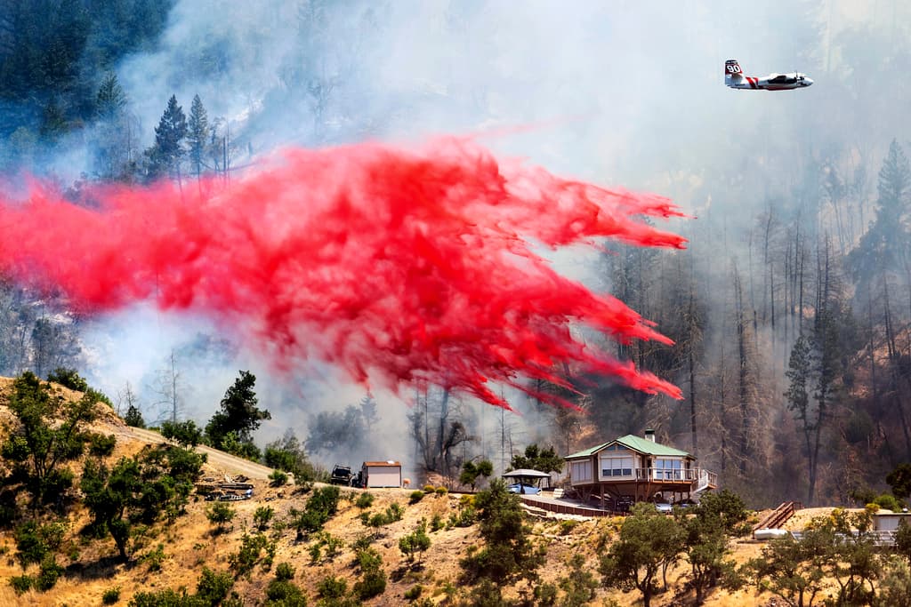 Los bomberos están combatiendo incendios forestales en el norte de California. La magnitud de los incendios ha requerido la movilización de múltiples equipos de bomberos de diferentes regiones. En la imagen, un avión cisterna arroja retardante detrás de una casa mientras lucha contra el incendio Toll cerca de Calistoga, California.