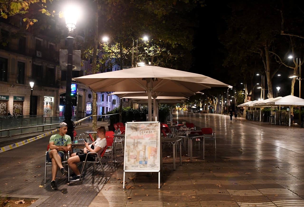 Dos hombres hablan en el área completamente vacía de la Rambla. El paseo de la Rambla está en el corazón de la ciudad y es una de las calles más transitadas. Normalmente está llena de turistas y artistas callejeros hasta altas horas de la noche.