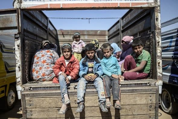 Niños kurdos se sientan en un camión después de cruzar la frontera sirio-turca en Suruc.