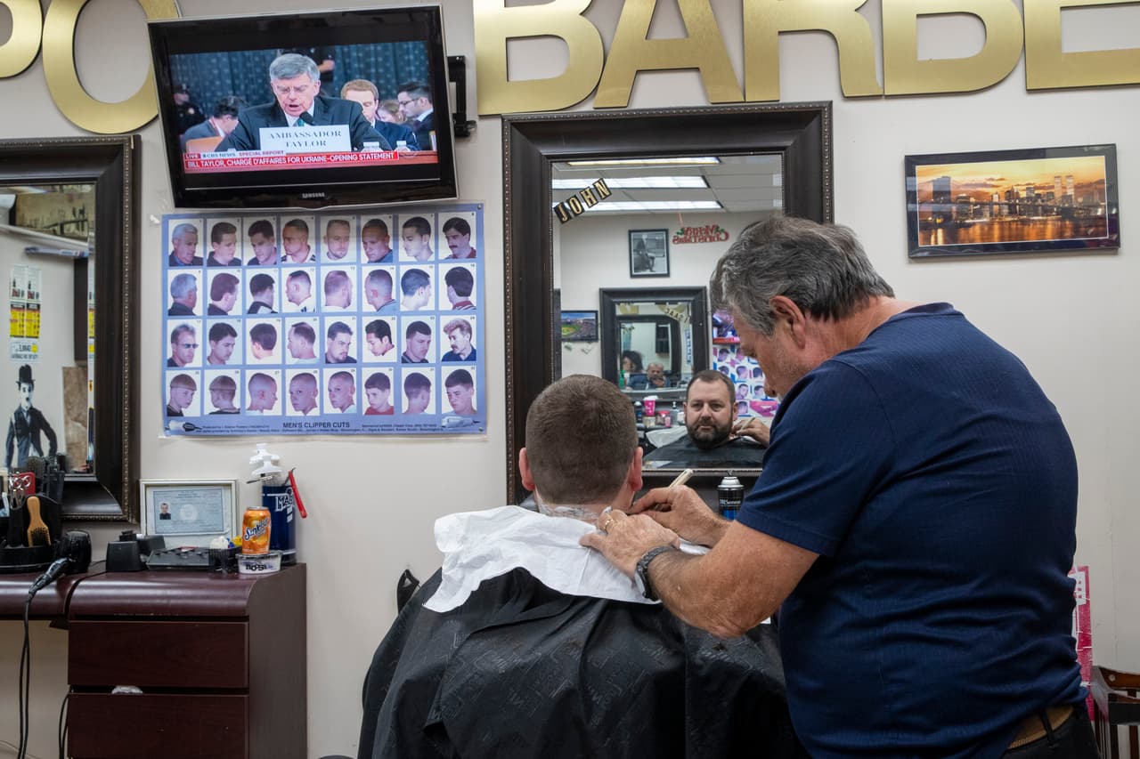 John Enea le corta el pelo a Kenneth Gary mientras miran la audiencia en una barbería de Manhattan, Nueva York. "Una completa farsa de juicio político", tuiteó el presidente al comienzo de la jornada, como lo hace prácticamente todos los días.