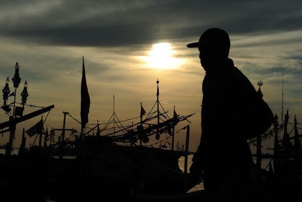 Un pescador indonesio camina el amanecer en la playa de Puerto Muncar.