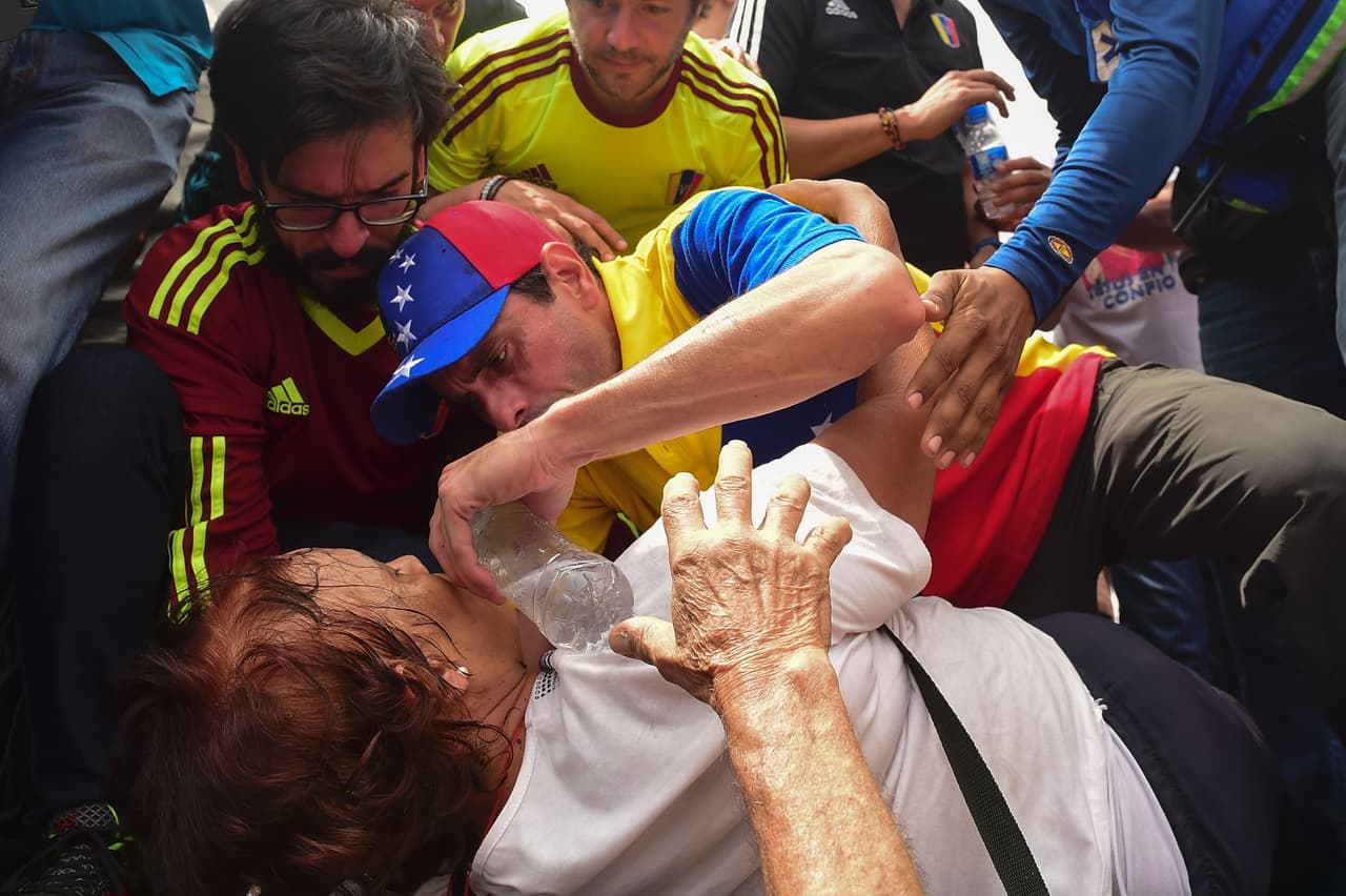 El líder opositor Henrique Capriles Radonski ayuda a una manifestante que se desmayó junto a él durante la marcha. Estas protestas son parte de las 
<b><a href="http://www.univision.com/temas/crisis-en-venezuela">medidas de presión anunciadas</a></b> para que el gobierno reactive el proceso de referendo revocatorio contra el presidente Nicolás Maduro.