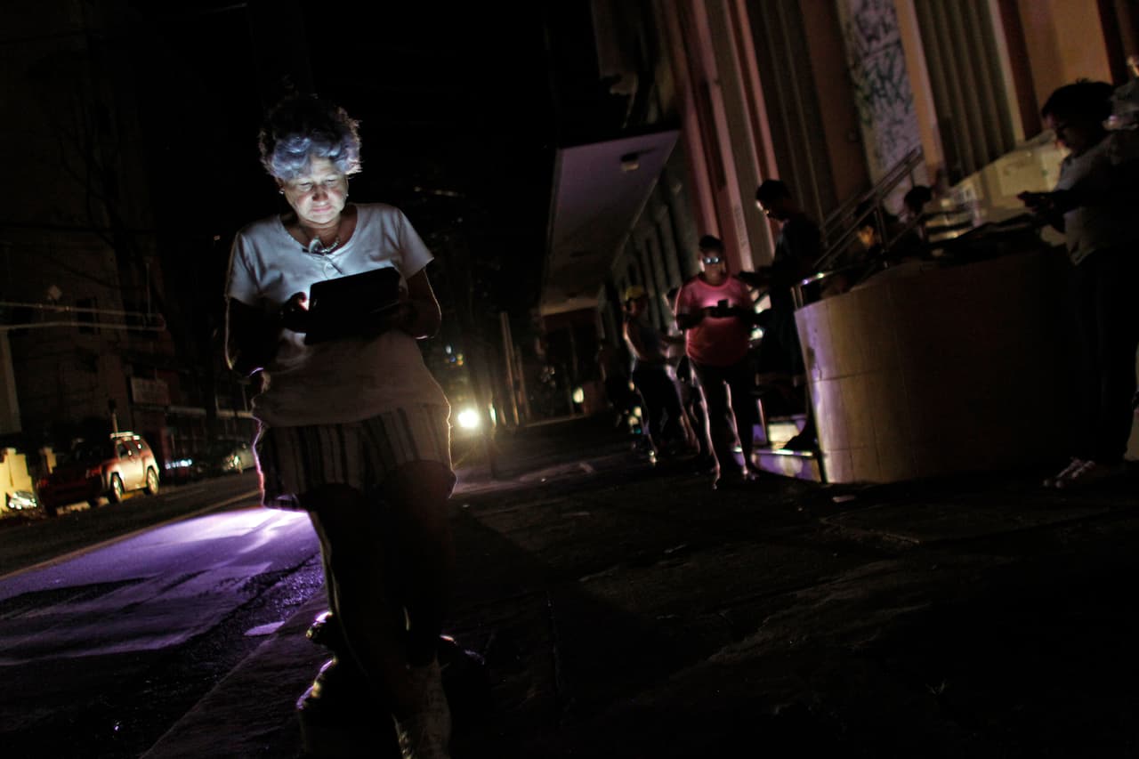 <b>Telecomunicaciones: 62%</b>. Los boricuas se han acostumbrado a conectarse en ciertos lugares donde encuentran señal de datos de teléfono, o donde un Wi-Fi esté libre. En la imagen tomada el 25 de septiembre de 2017, varios residentes de San Juan utilizan sus tabletas en una calle oscura de la ciudad.