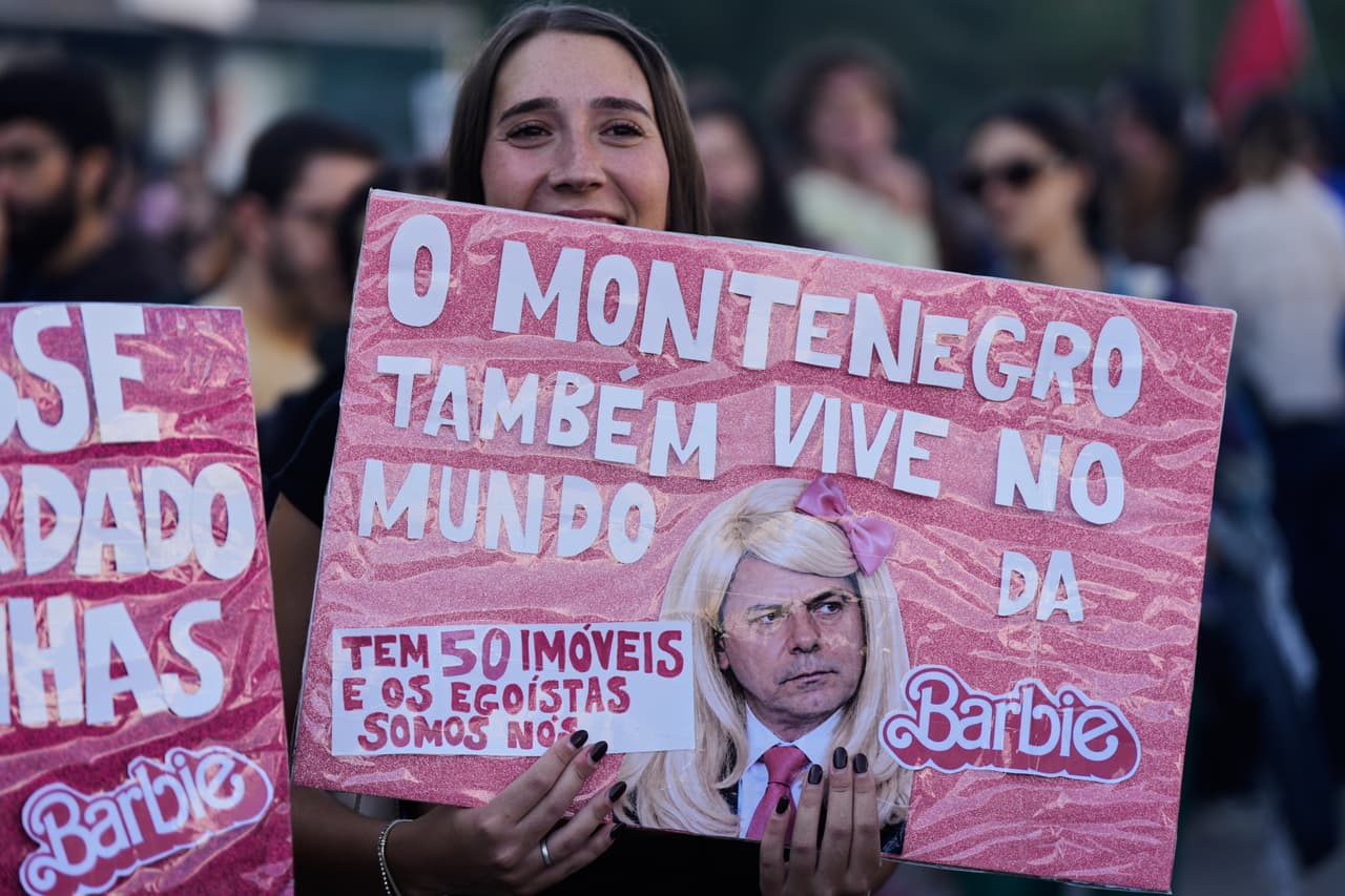 Una mujer sostiene una pancarta que hace referencia al primer ministro portugués, Luis Montenegro, durante una protesta para exigir viviendas asequibles en Lisboa el sábado 24 de octubre de 2026. El texto dice en portugués: "Montenegro también vive en el mundo de Barbie. Él tiene 50 propiedades, y sin embargo, nosotros somos los egoístas".