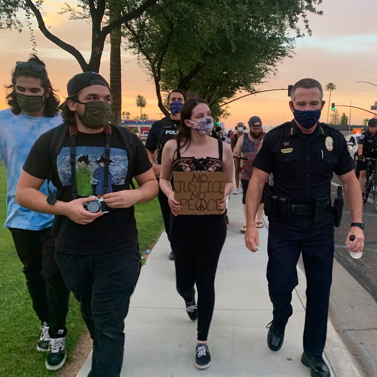 Con un letrero en el que se lee “sin justicia, no hay paz " una mujer marcha al lado del jefe de la policía de Chandler. 
<br>