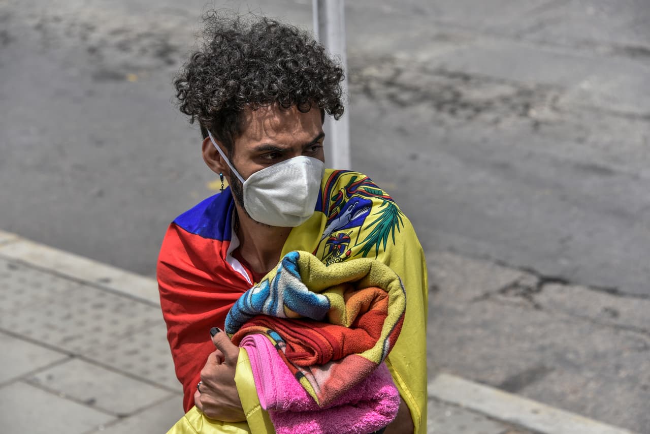 "Yo prefiero pasar trabajo con mi mamá que pasar trabajo en otro país", dijo uno de los migrantes a la agencia EFE. En la fotografía un venezolano abrigado con la bandera su país en un descanso de la caminata a las afueras de Bogotá.
