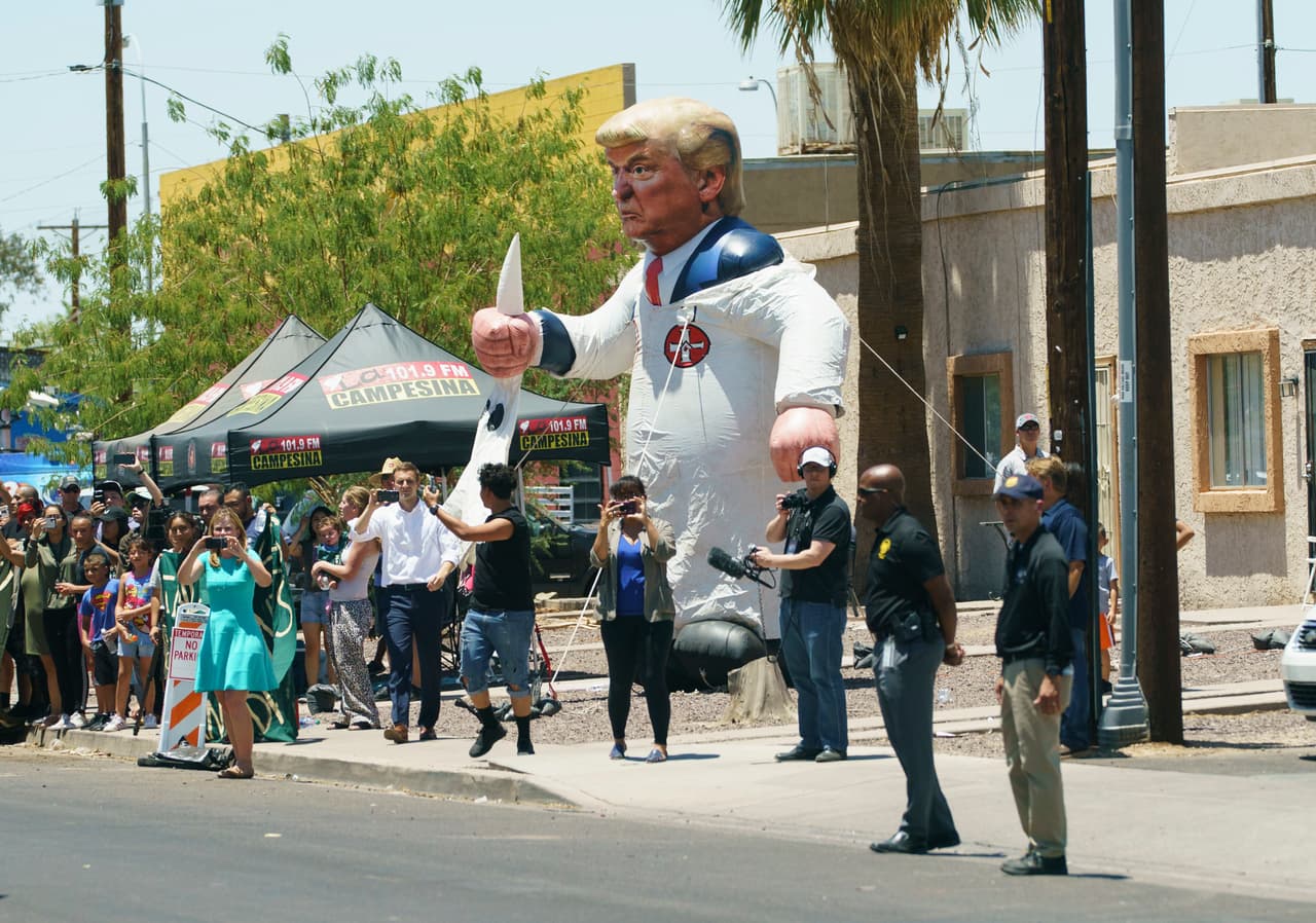 Los manifestantes colocan un globo inflable con la figura del presidente Donald Trump vestido con una sábana del Ku Klux Klan al otro lado de la calle de Southwest Key Campbell, un albergue para niños que han sido separados de sus padres, en Phoenix, Arizona, durante una visita de la primera dama Melania Trump. (AP Photo / Carolyn Kaster)